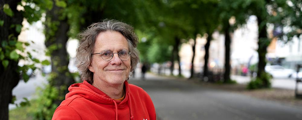 Olof sittandes utomhus i en grön allé